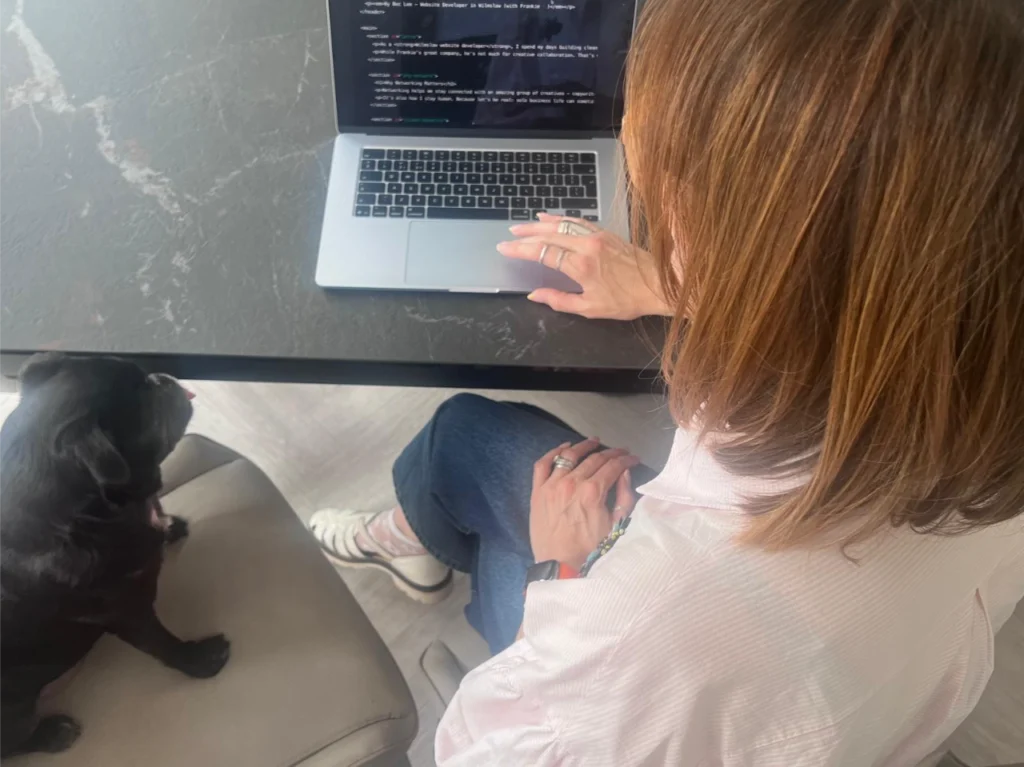 Image of Bec working on code for a WordPress website, sat with Frankie the pug.